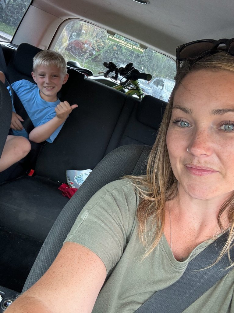 Jay Whitfield sitting in a car with her seven-year-old son, both watching screens